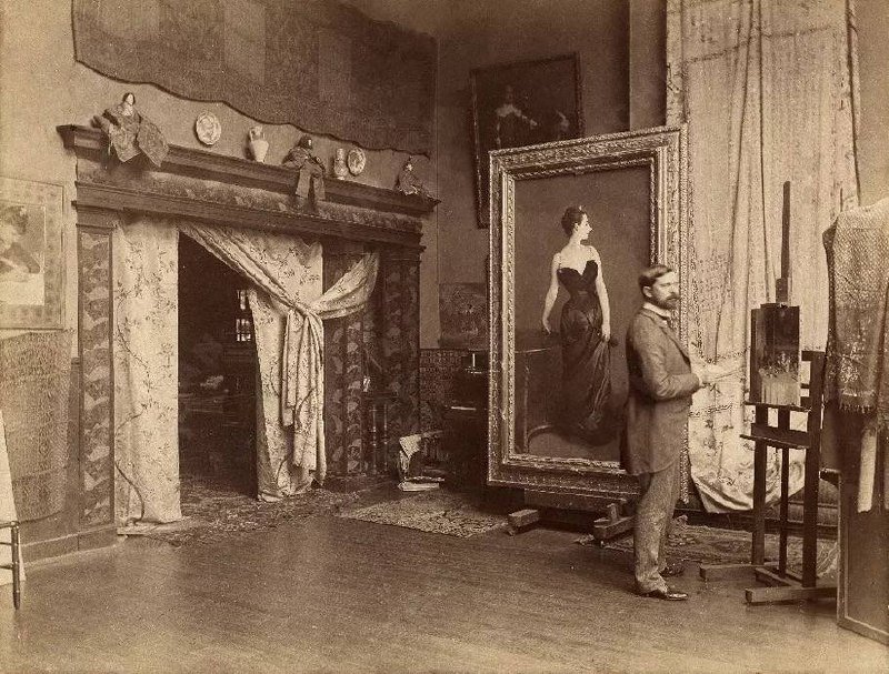 Historical photograph of John Singer Sargent in his studio beside the framed Madame X portrait.